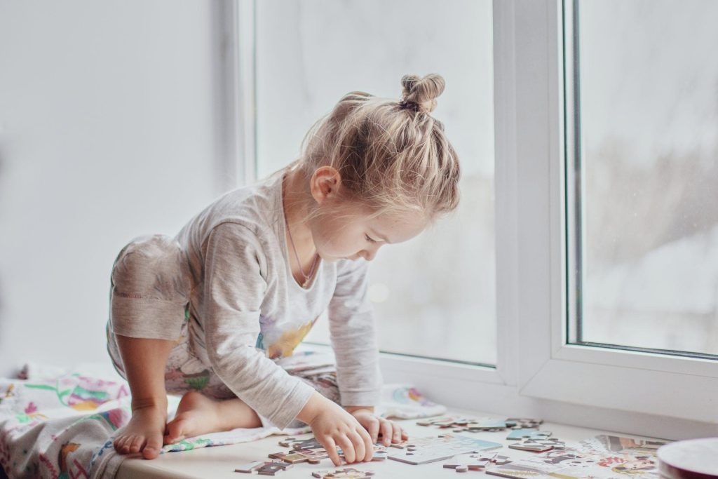 little girl collects puzzles by the window in ligh 2021 12 15 21 03 37 utc scaled 1